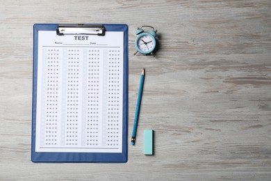 Photo of Clipboard with answer sheet, pencil and alarm clock on light wooden table, flat lay and space for text. Student passing exam