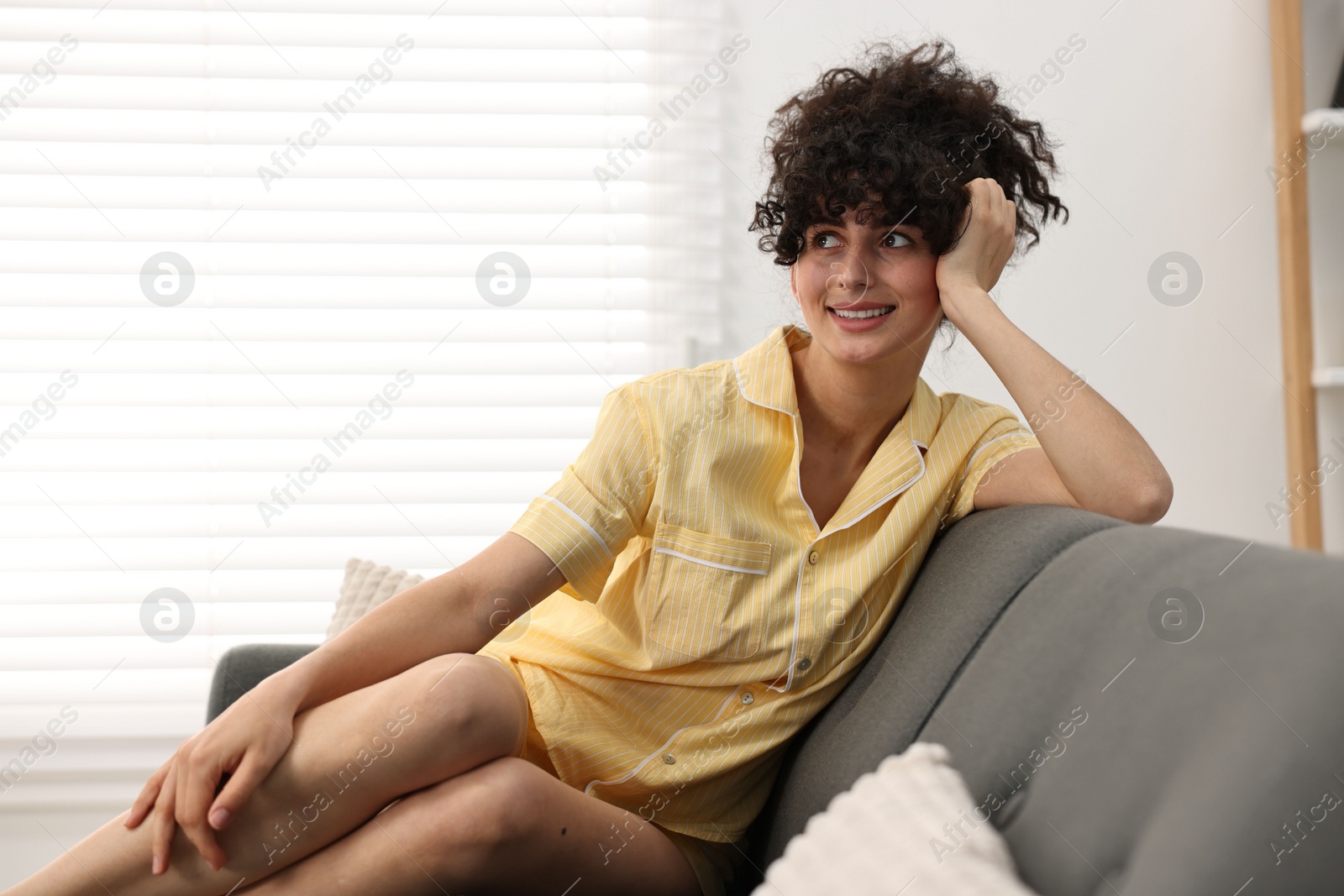 Photo of Beautiful young woman in stylish pyjama on sofa at home