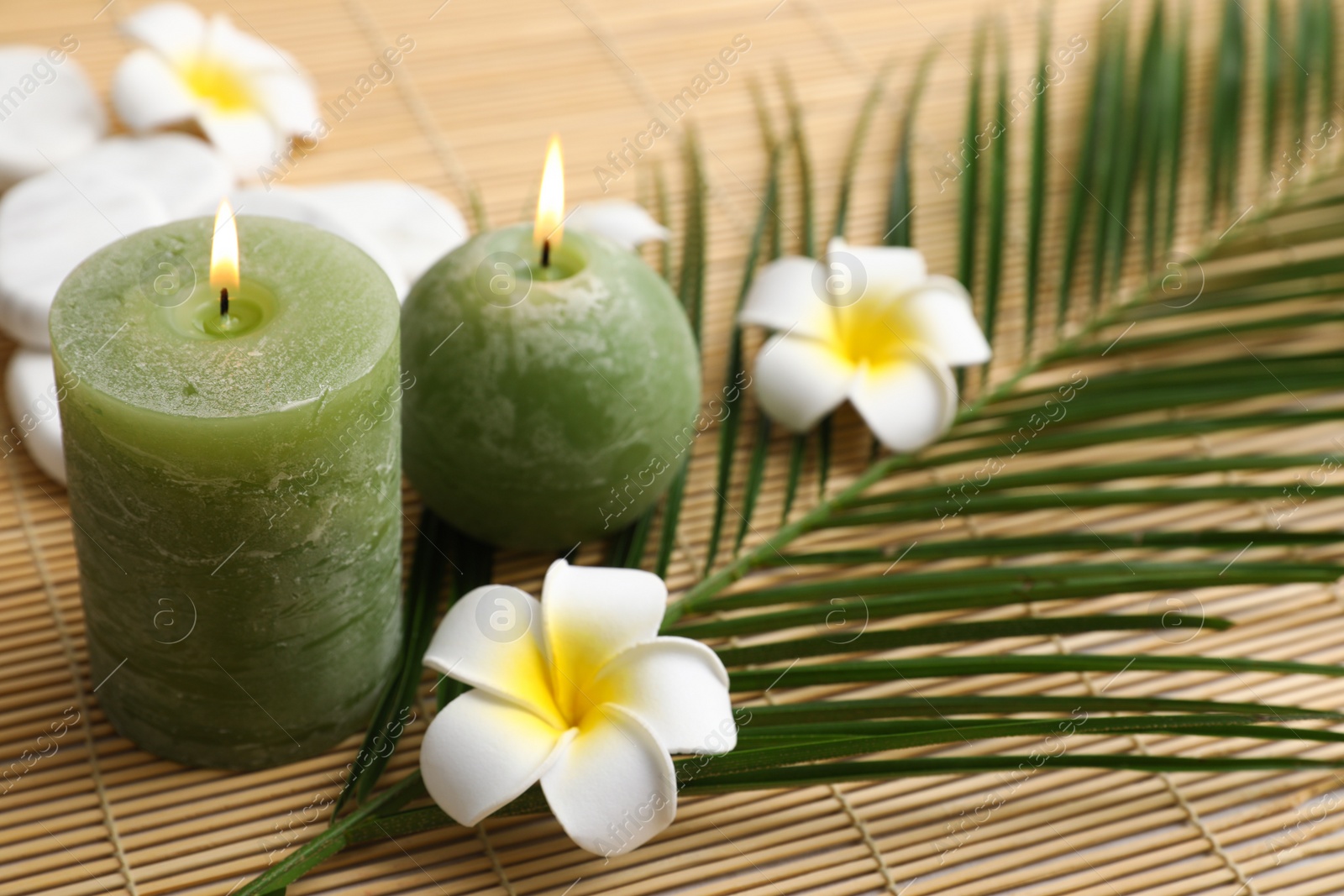 Photo of Composition with spa stones, flowers and candles on bamboo mat