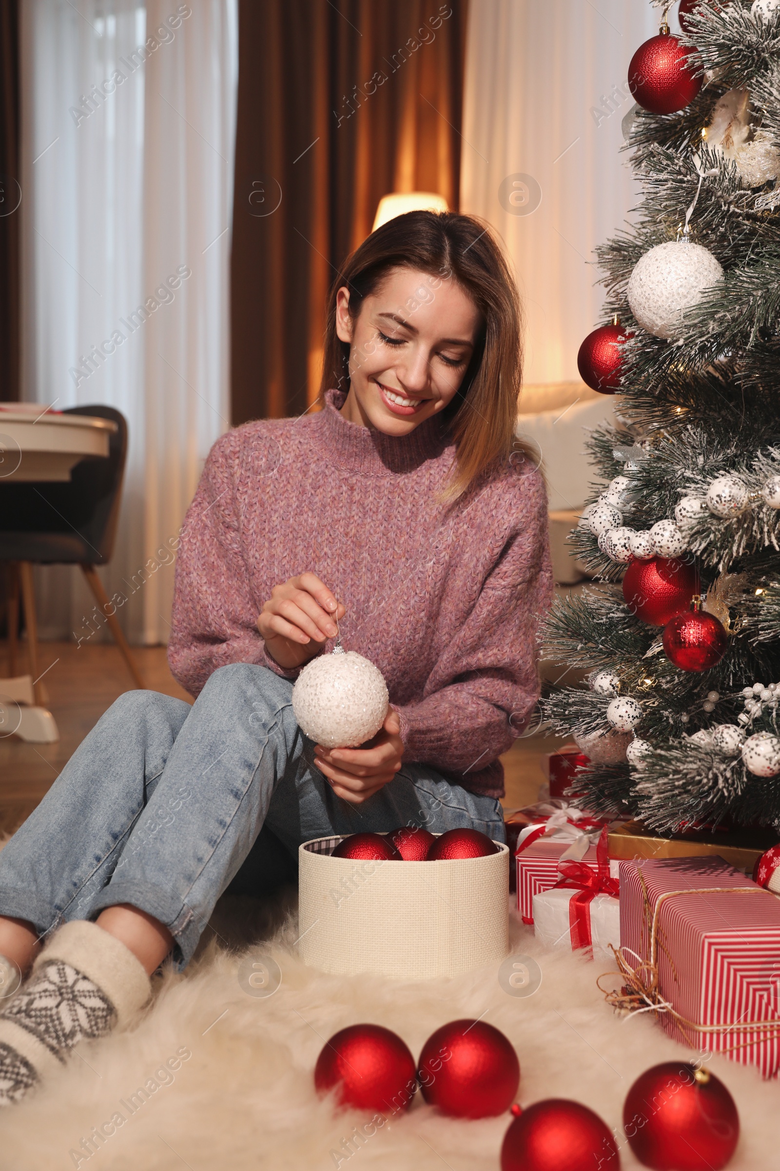 Photo of Young woman decorating Christmas tree at home