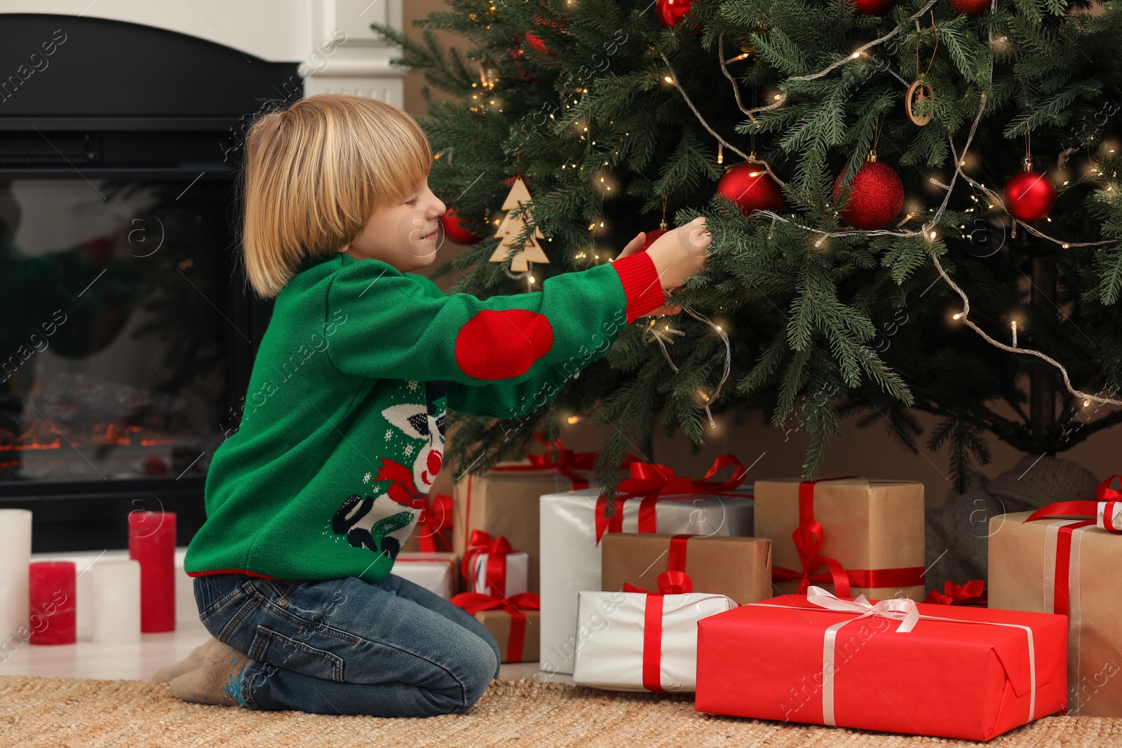 Photo of Little child decorating Christmas tree at home