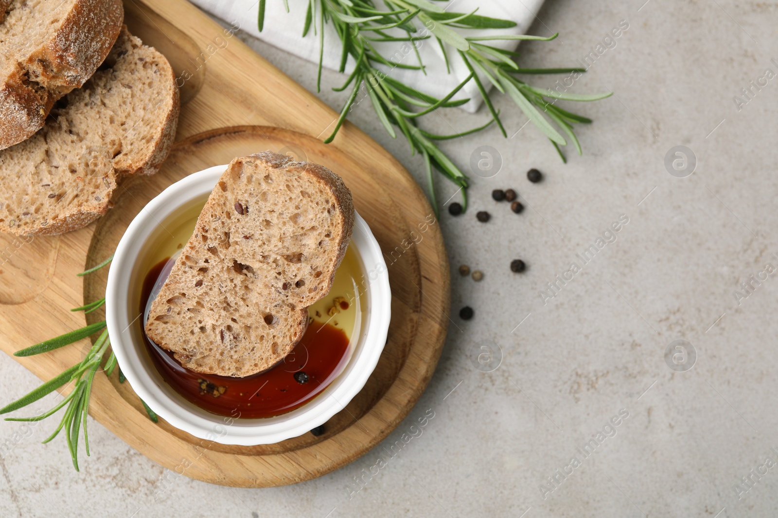 Photo of Bowl of organic balsamic vinegar with oil served with spices and bread slices on beige table, flat lay. Space for text