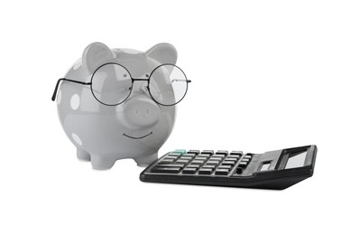 Photo of Calculator and grey piggy bank in glasses isolated on white