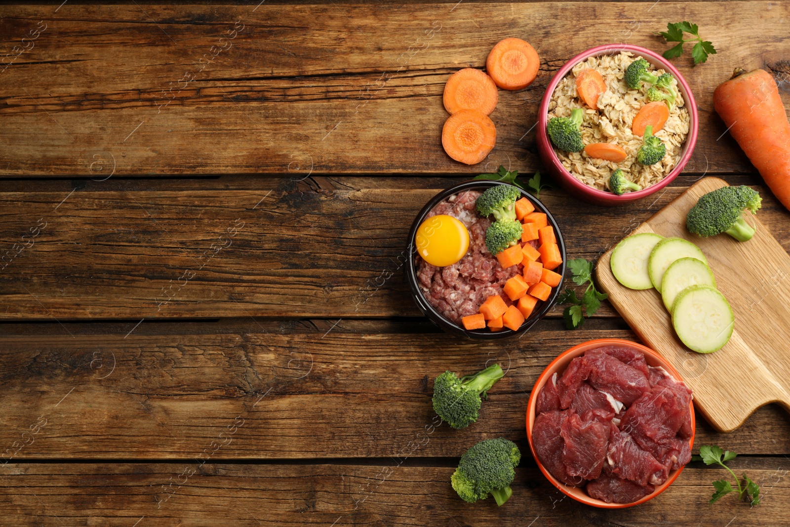 Photo of Pet food and natural ingredients on wooden table, flat lay. Space for text