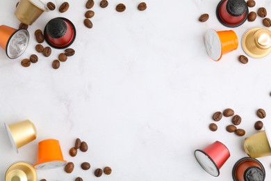 Photo of Many coffee capsules and beans on white marble table, flat lay. Space for text