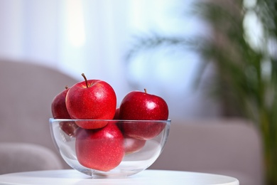 Bowl of fresh red apples on table indoors. Space for text