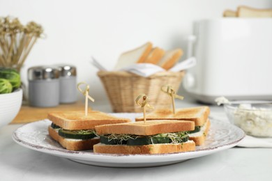 Tasty sandwiches with cucumber and microgreens on white table, closeup