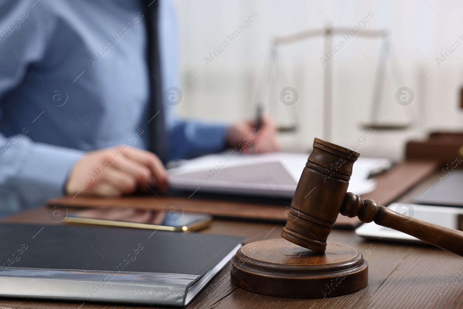 Photo of Lawyer working with documents at wooden table, focus on gavel