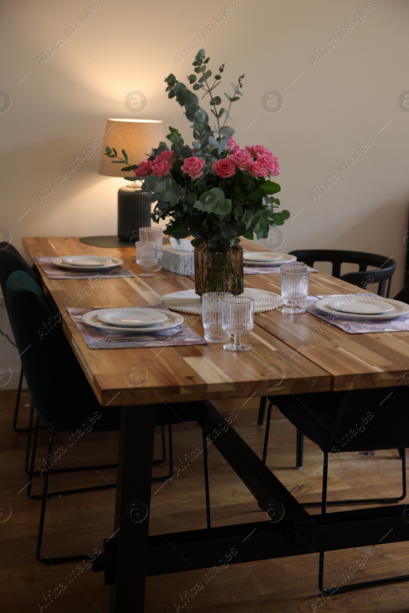 Photo of Beautiful table setting with bouquet indoors. Roses and eucalyptus branches in vase