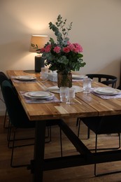 Beautiful table setting with bouquet indoors. Roses and eucalyptus branches in vase