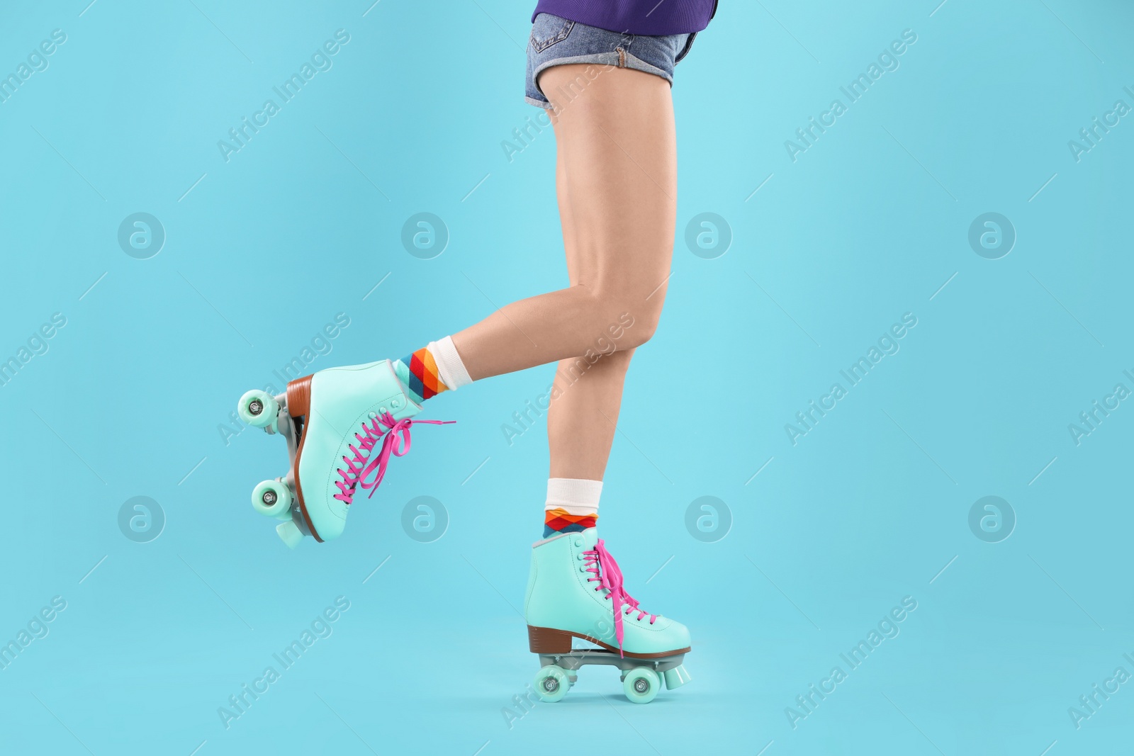 Photo of Young woman with retro roller skates on color background, closeup