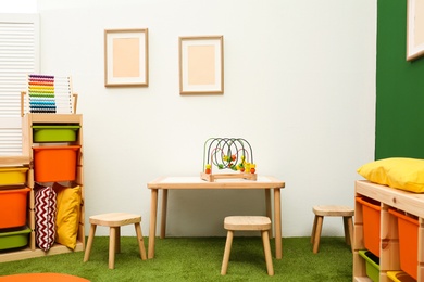 Photo of Stylish playroom interior with table and stools