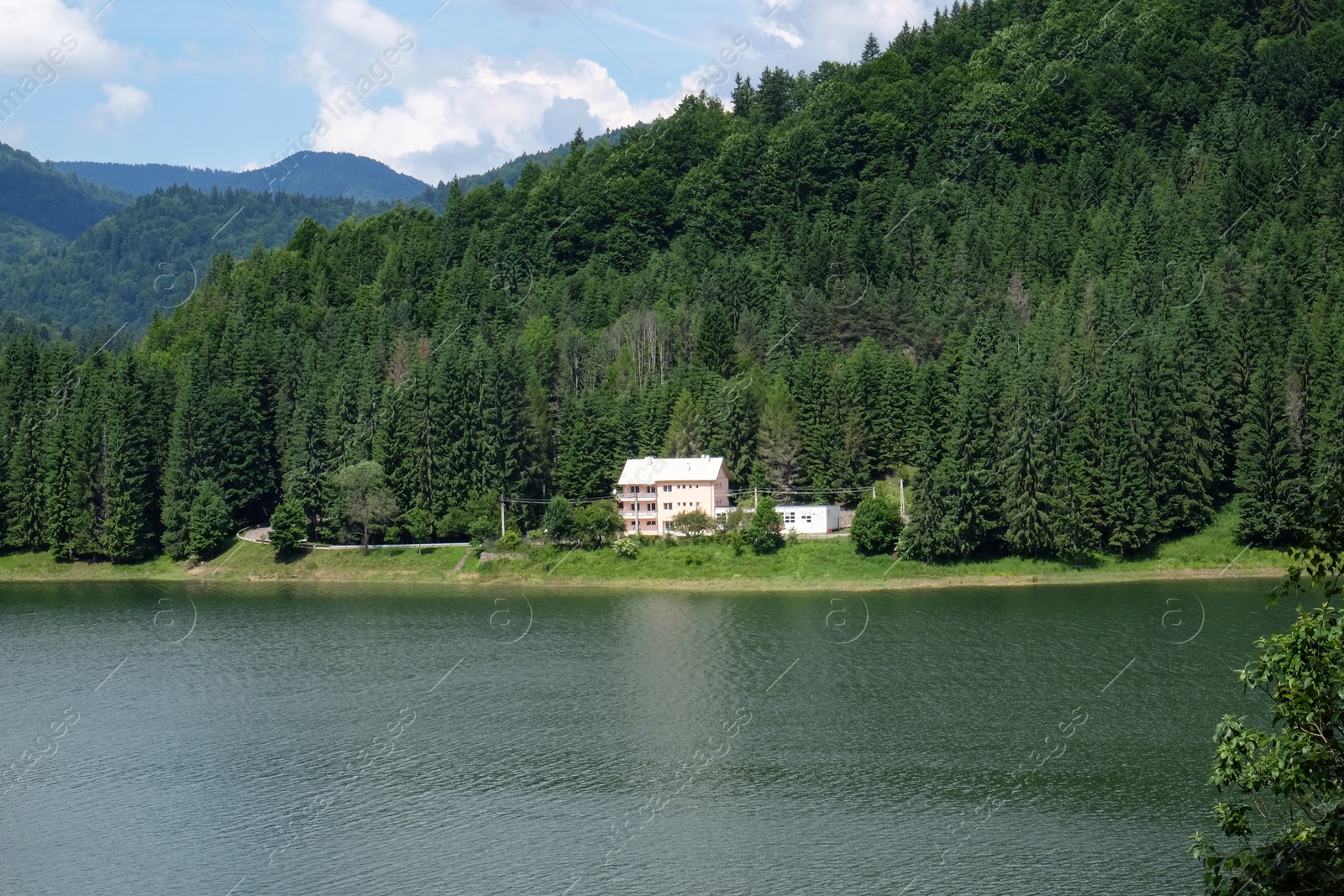 Image of Lonely house in green forest at bottom of hill near lake