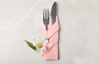 Photo of Folded napkin with fork, knife and flower on table, top view