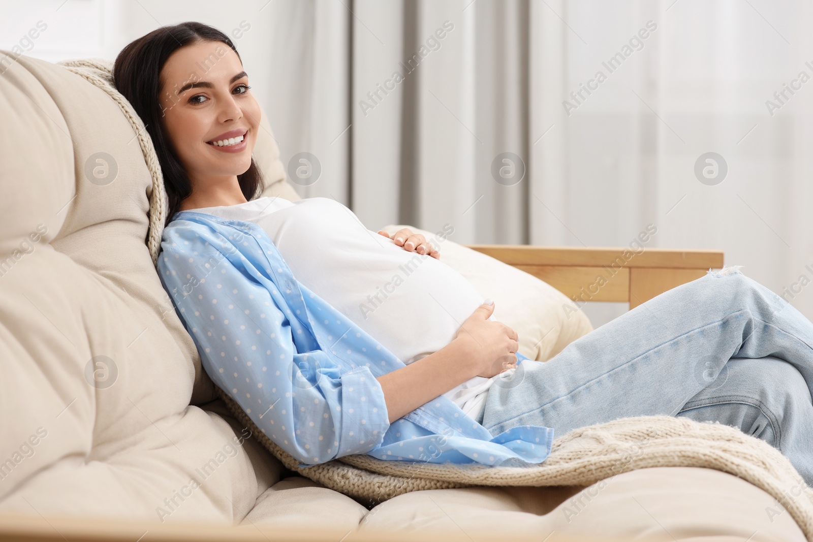 Photo of Happy pregnant woman on sofa at home