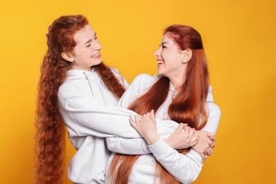 Photo of Portrait of beautiful young redhead sisters on orange background