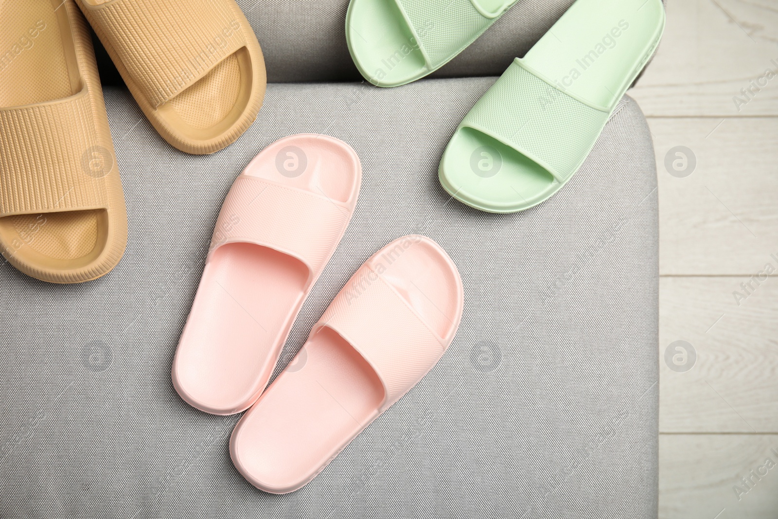 Photo of Pairs of stylish rubber slippers indoors, top view