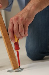 Man with screwdriver assembling furniture on floor, closeup