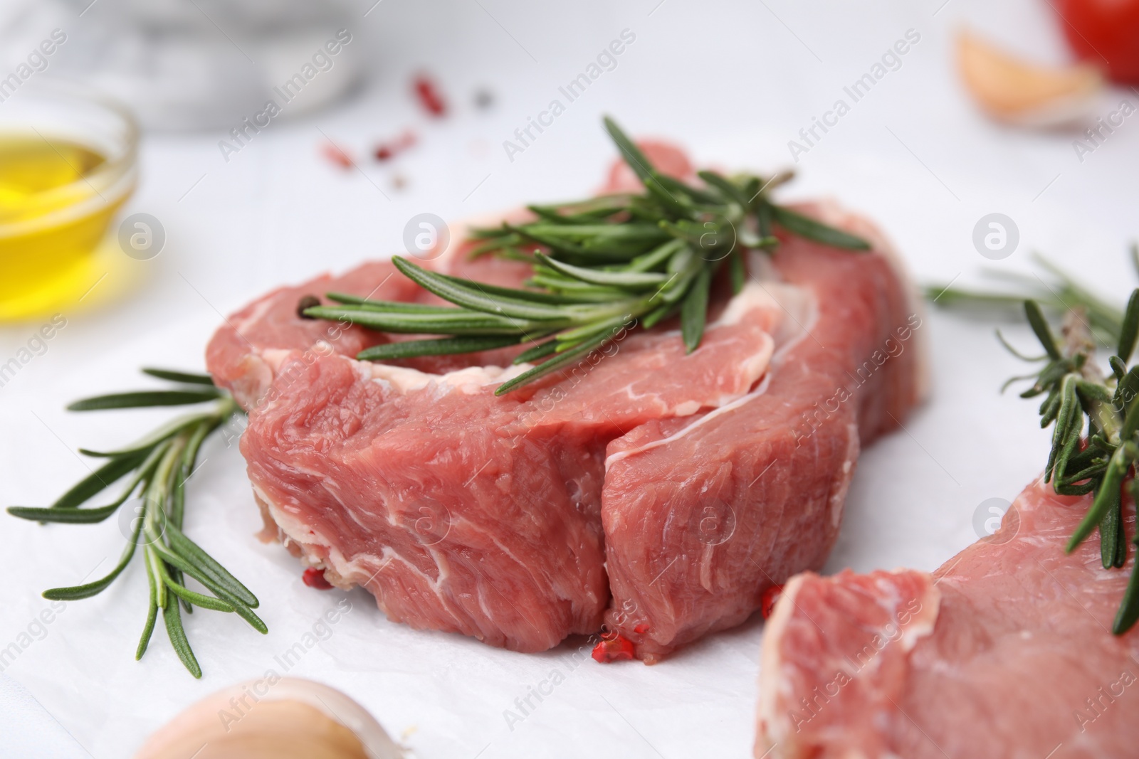 Photo of Fresh raw meat with rosemary on parchment paper, closeup