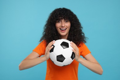 Photo of Excited fan holding soccer ball on light blue background