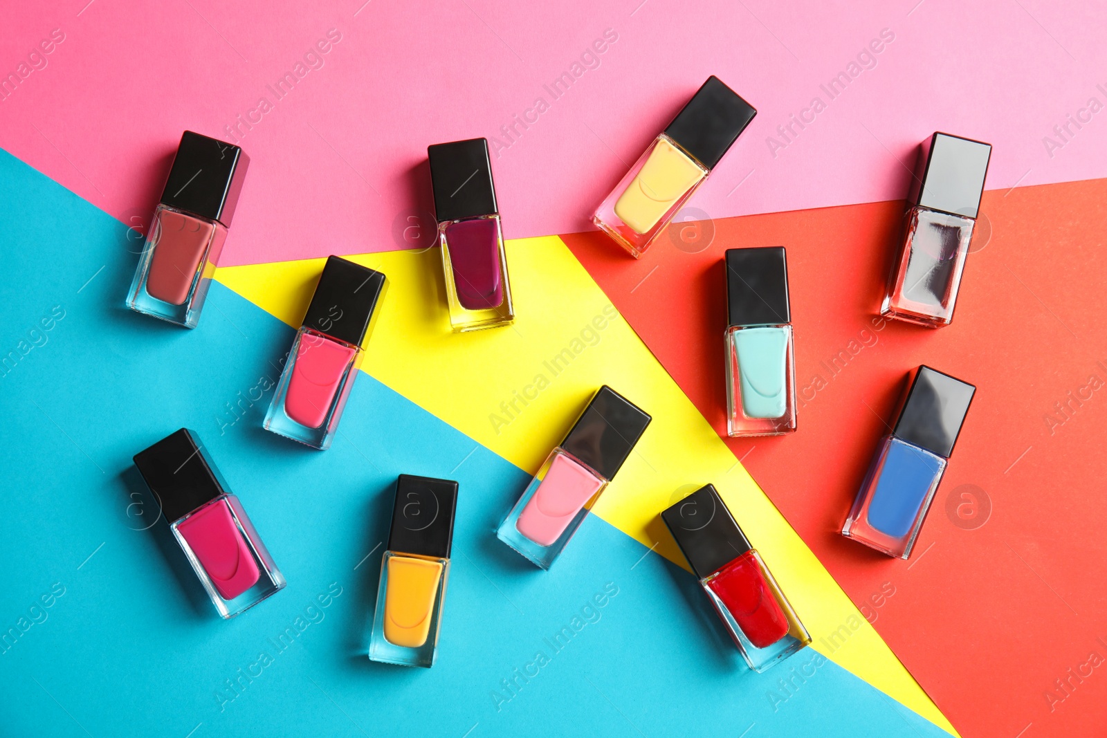 Photo of Bottles of nail polish on color background, top view