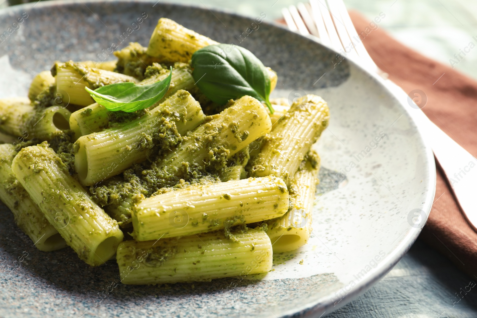 Photo of Plate with delicious basil pesto pasta on table
