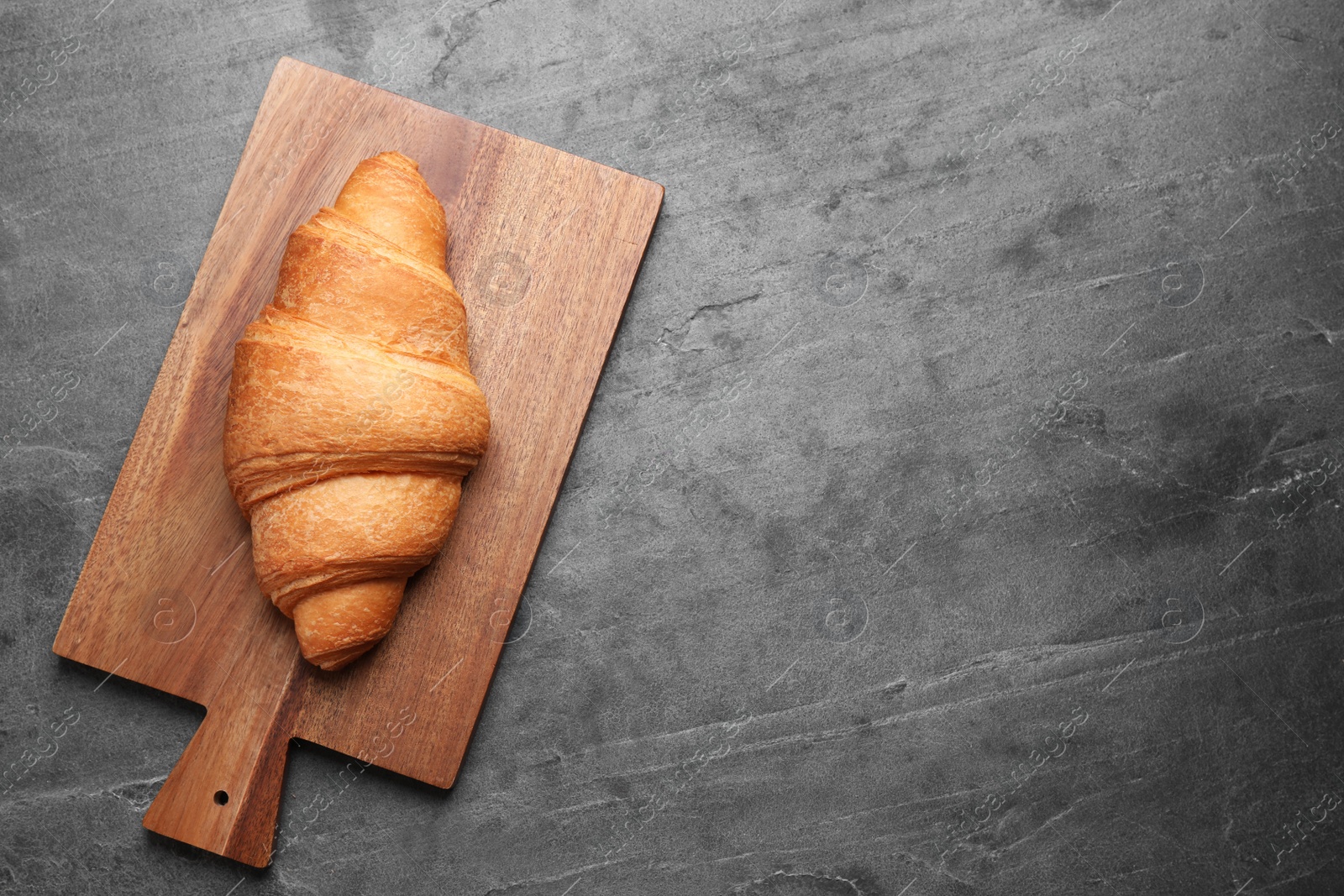 Photo of Tasty fresh croissant on grey table, top view. Space for text