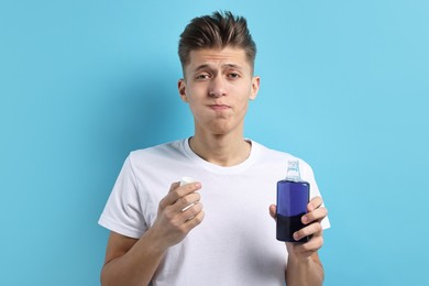 Photo of Young man using mouthwash on light blue background