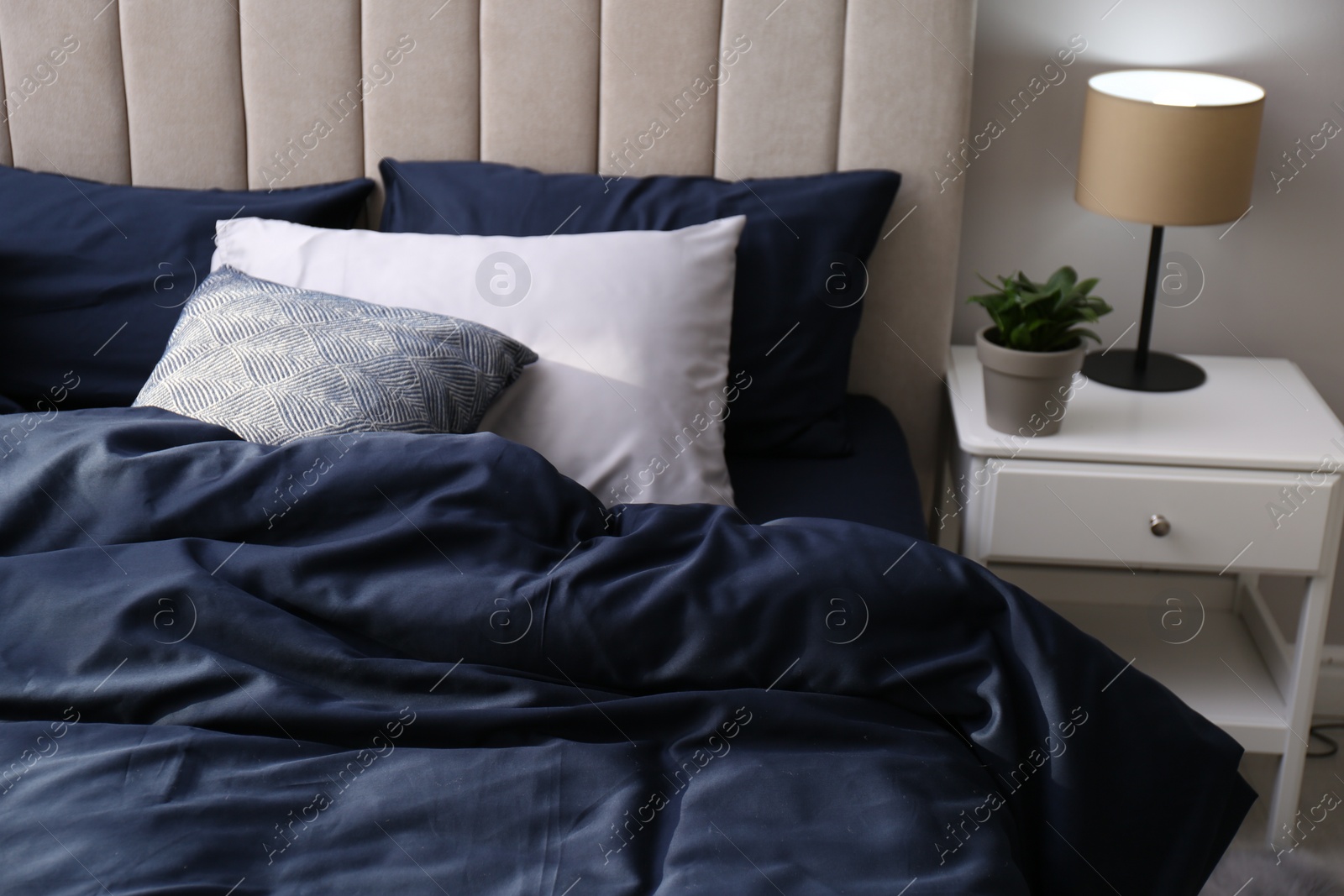 Photo of Bed with stylish silky linens in room