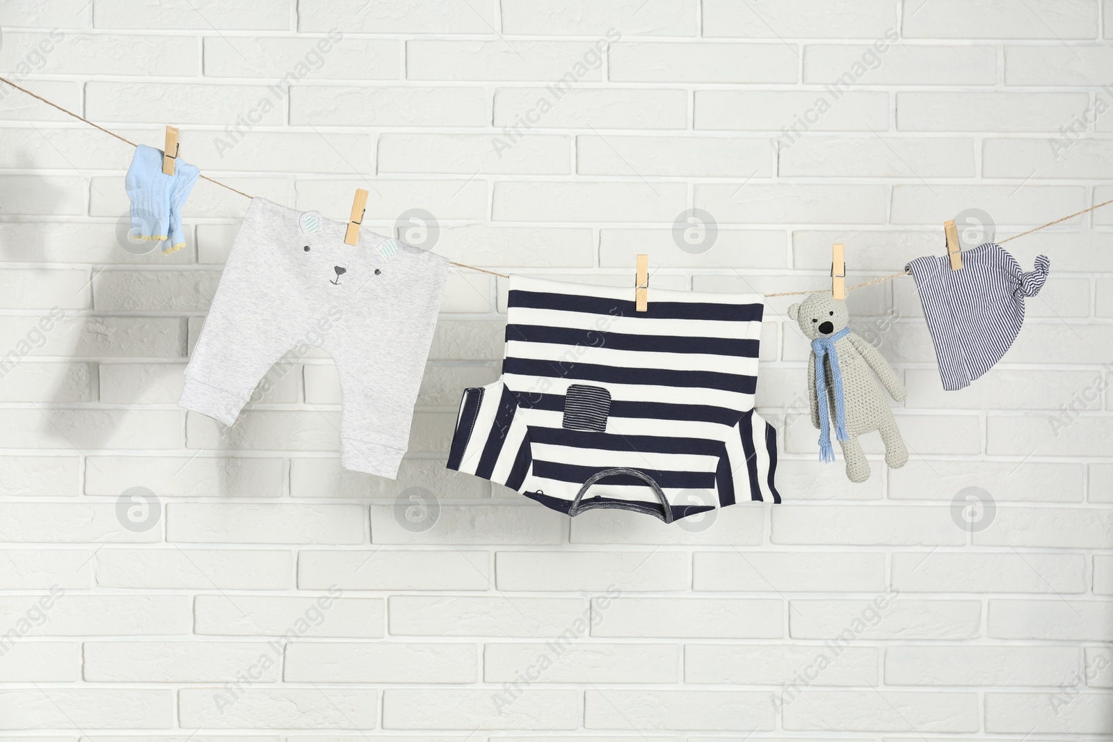 Photo of Baby clothes hanging on washing line near white brick wall