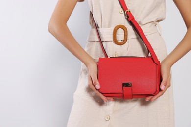 Photo of Woman with stylish red bag on light grey background, closeup