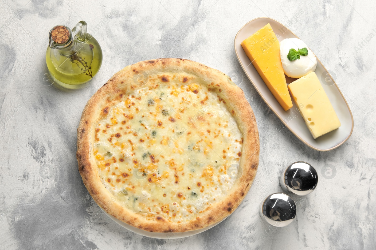 Photo of Delicious cheese pizza, oil and different kinds of cheese on light grey textured table, flat lay