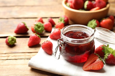 Photo of Delicious pickled strawberry jam and fresh berries on wooden table