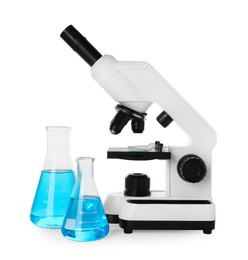 Photo of Laboratory glassware with light blue liquid and microscope isolated on white