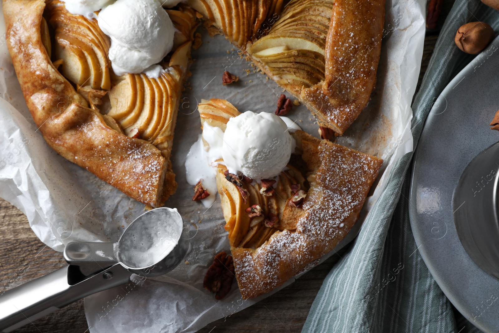 Photo of Delicious apple galette served with ice cream on wooden table, flat lay