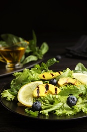 Delicious avocado salad with lemon and blueberries on black table