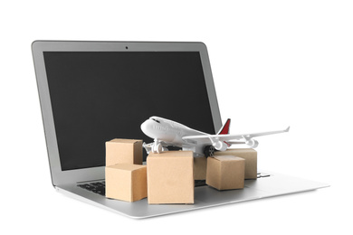 Photo of Laptop, airplane model and carton boxes on white background. Courier service