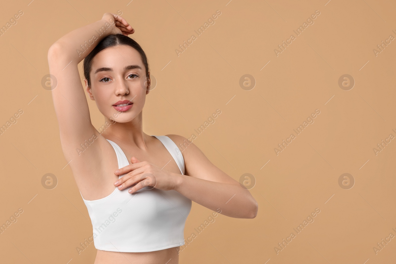 Photo of Beautiful woman showing armpit with smooth clean skin on beige background, space for text