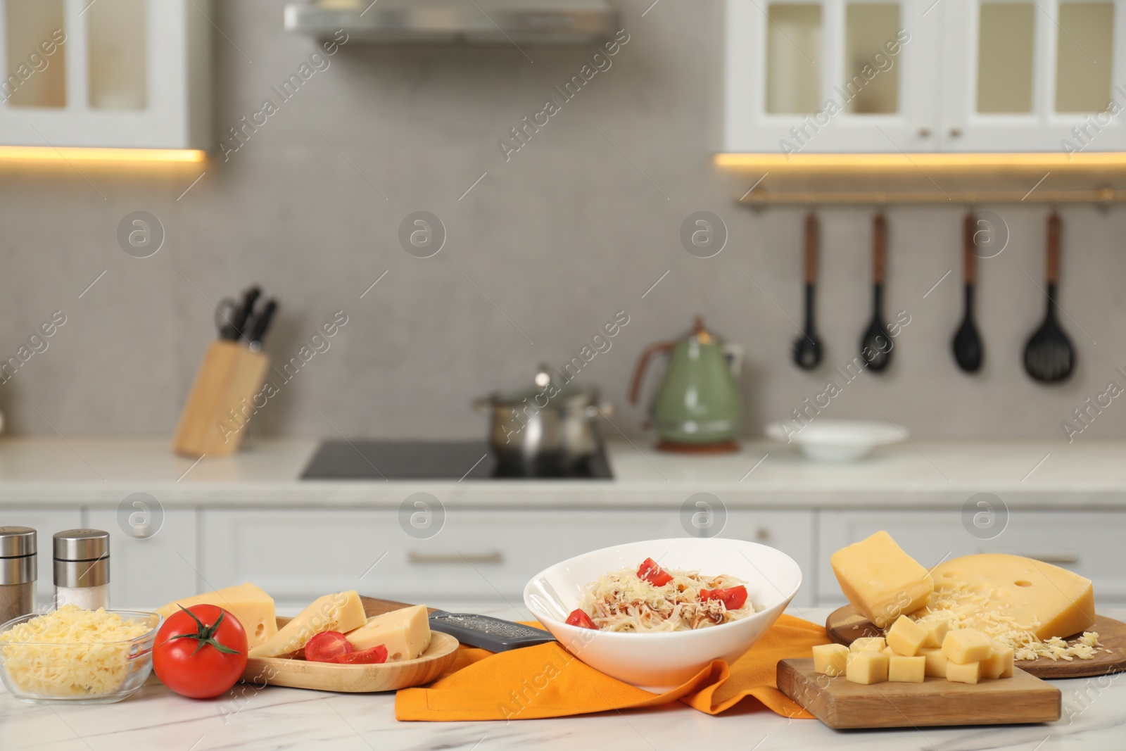 Photo of Delicious pasta with grated cheese and tomatoes on white marble table in kitchen
