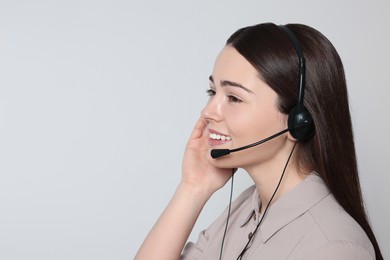 Hotline operator with modern headset on light grey background, space for text. Customer support