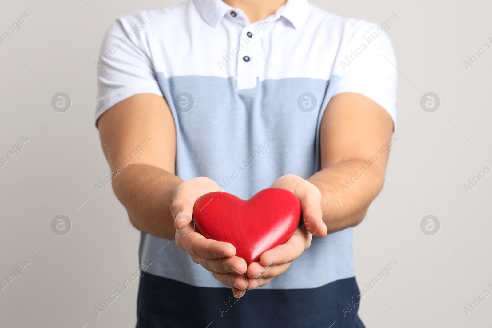 Photo of Man holding decorative heart on light background, closeup