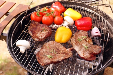 Photo of Modern grill with meat and vegetables outdoors, closeup