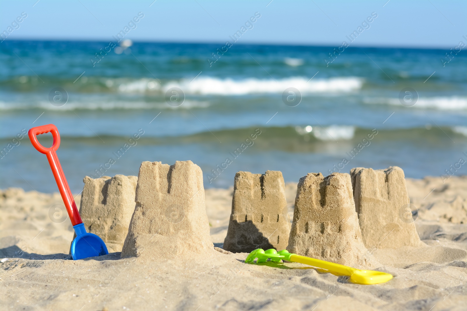 Photo of Beautiful sand castles and child plastic toys on beach near sea