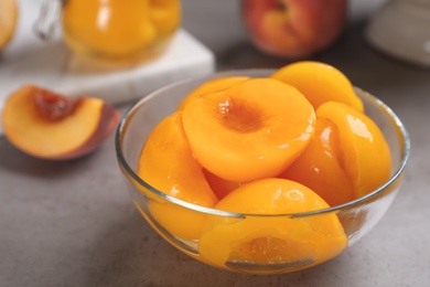 Photo of Glass bowl with conserved peach halves on grey table