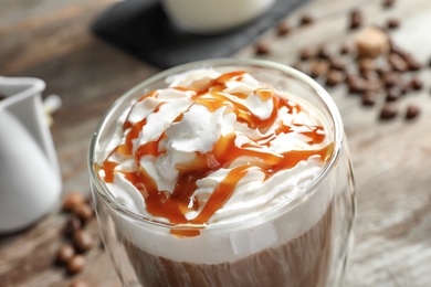 Glass of coffee with caramel topping on table, closeup