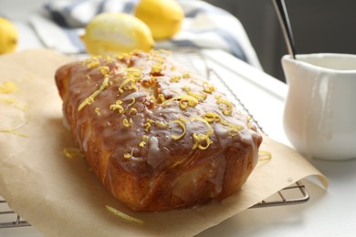Photo of Tasty lemon cake with glaze on white table, closeup