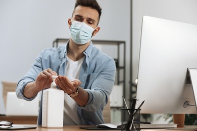 Photo of Man applying sanitizer in office, focus on hands. Personal hygiene during Coronavirus pandemic