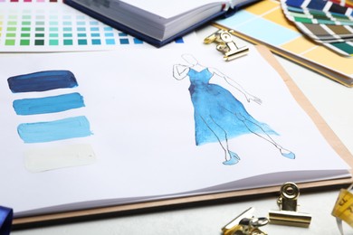 Photo of Drawing of dress on white table, closeup. Designer's workplace