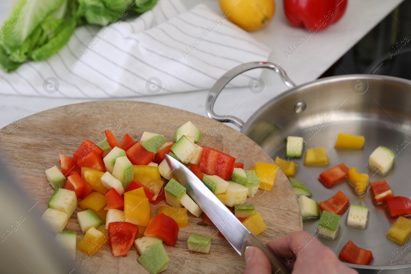 Photo of Woman putting cut vegetables into saute pan in kitchen, closeup