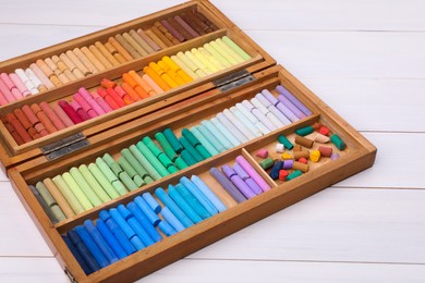 Set of soft pastels in box on white wooden table. Drawing material